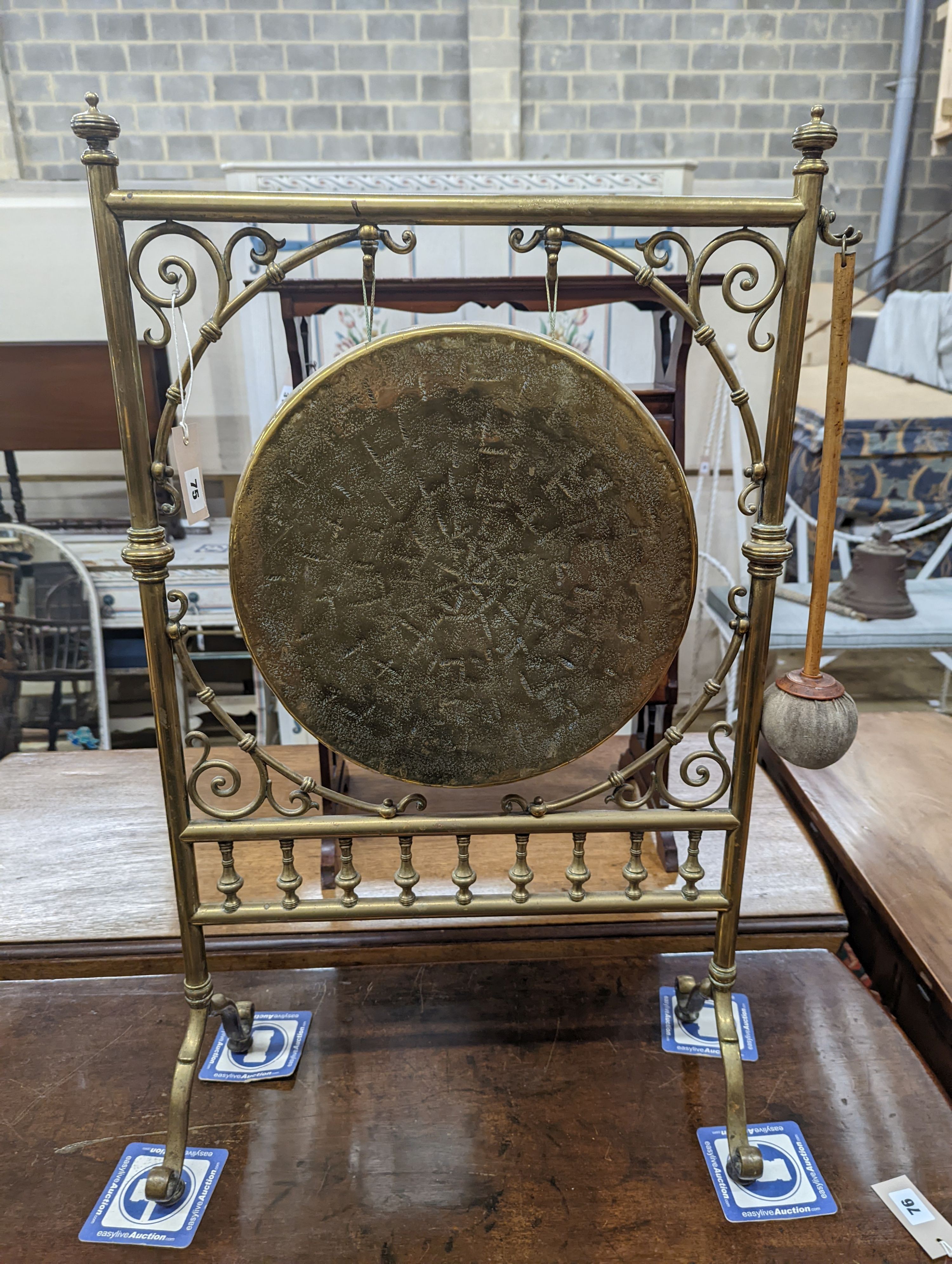 An Edwardian brass dinner gong with striker, width 50cm, height 84cm